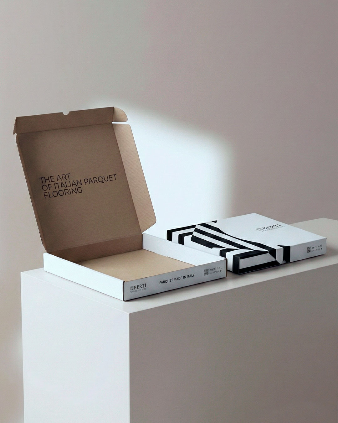 Dettaglio del packaging per campioni di parquet Berti con pattern geometrico bianco e nero derivato dal logo